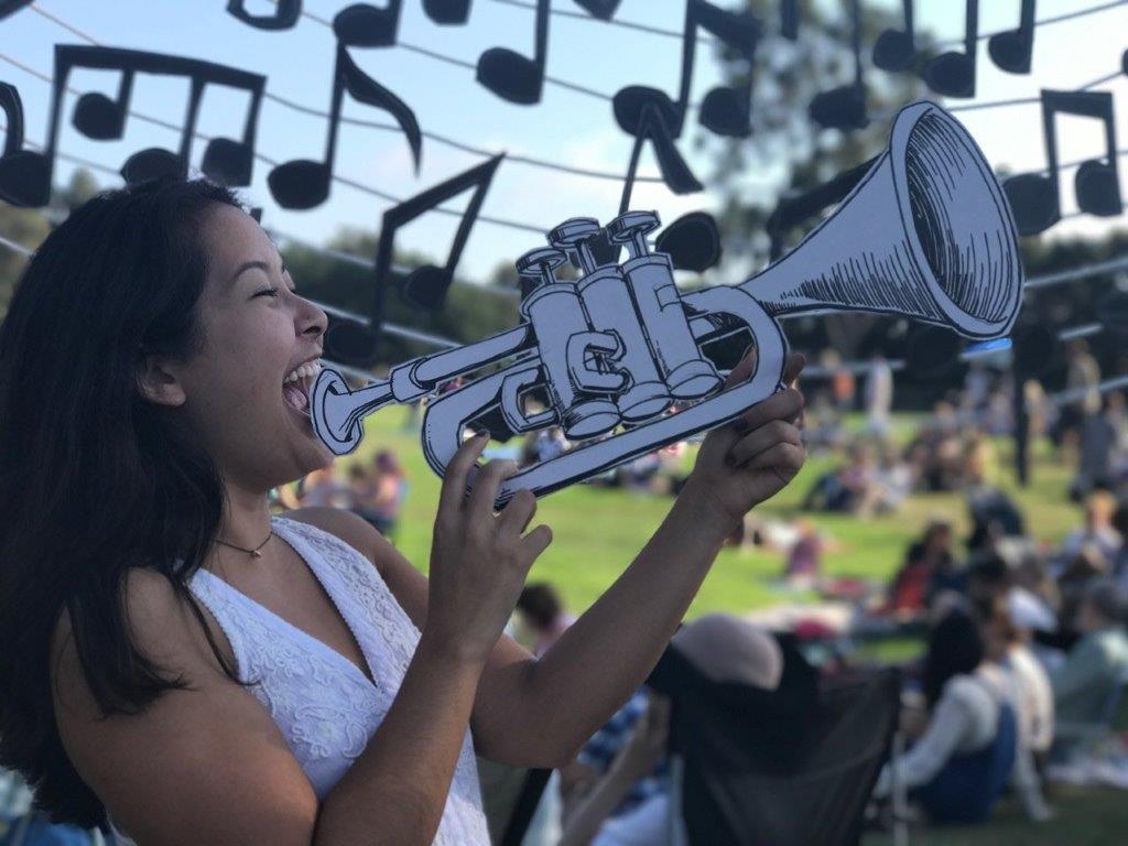 a participant poses with Kiel Johnson's cardboard cutouts, Jazz on the Lawn 2017